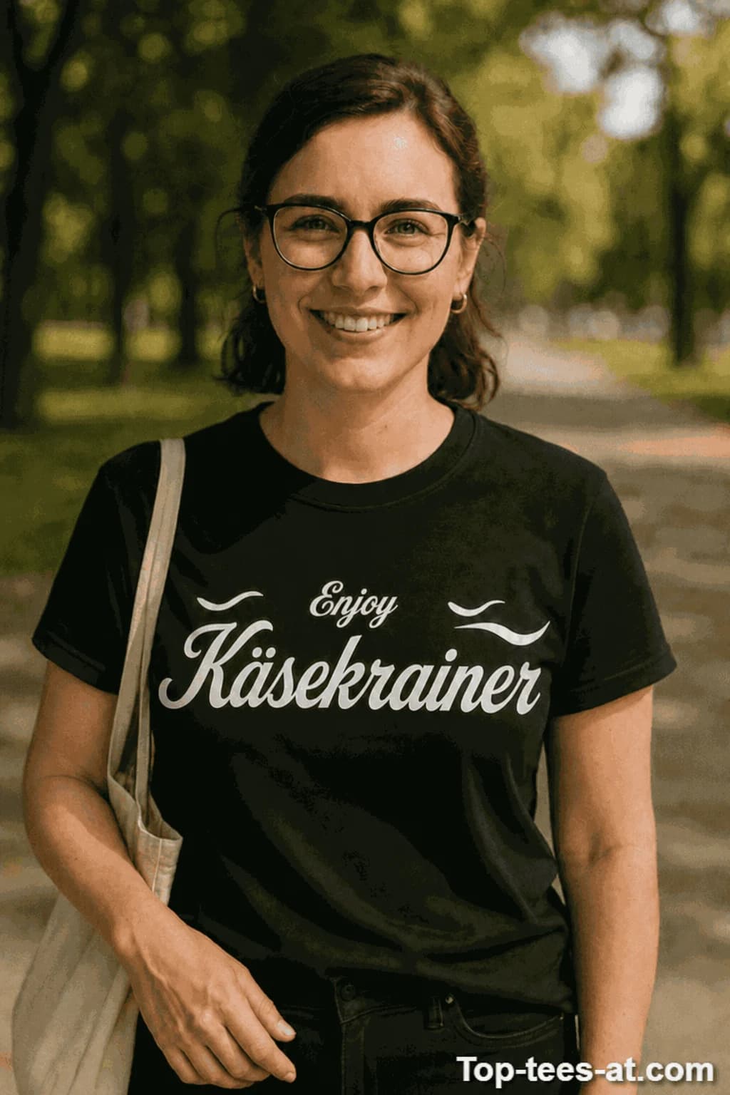 Frau mit Brille in schwarzem T-Shirt mit geschwungenem weißen Schriftzug „Enjoy Käsekrainer“ im Logo-Stil