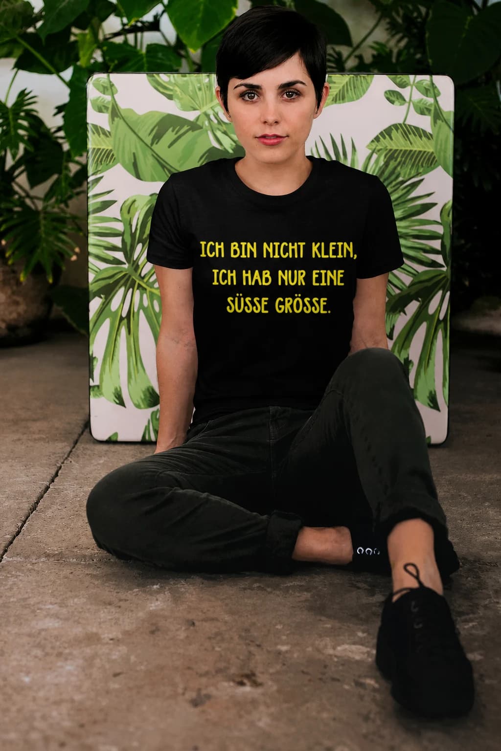 Schwarzes Damen-T-Shirt mit Spruch „Ich bin nicht klein, ich hab nur eine süße Größe.“, sitzende Frau