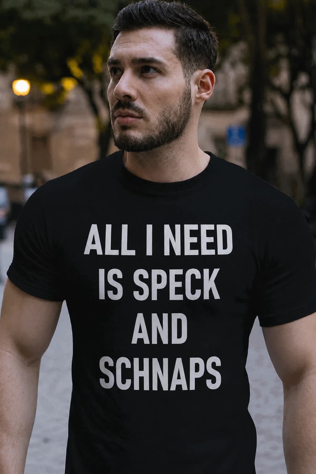 Mann im schwarzen T-Shirt mit weißem Spruch zur Lieblingsjause mit Speck und Schnaps